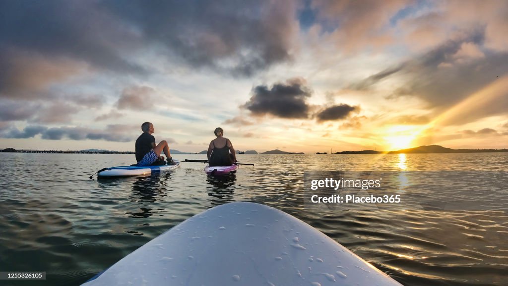 Deux femmes sur paddleboards admirant le coucher du soleil première personne POV
