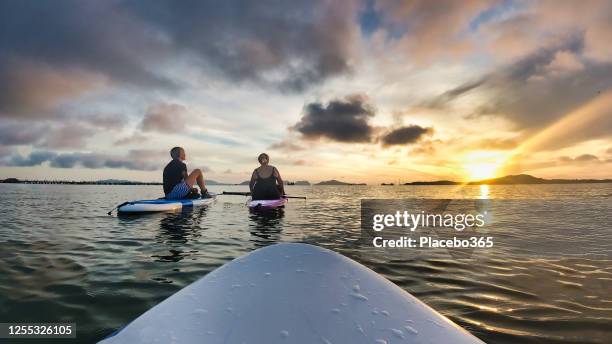twee vrouwen op paddleboards die zonsondergang eerste persoon pov bewonderen - personal perspective stockfoto's en -beelden