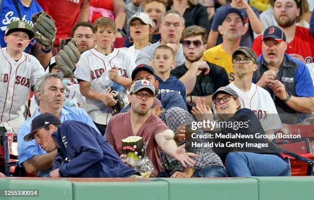 Red Sox fan tries to catch a foul ball during the third inning of the MLB game against the Seattle Mariners at Fenway Park on Tuesday in Boston , MA....