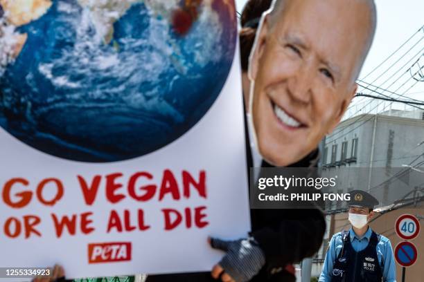 An activist from the animal rights group PETA Asia wearing a cutout of US President Joe Biden takes part in a protest to urge governments to...