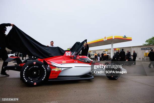 Team Abel members working for IndyCar driver R.C. Enerson cover his car to protect it from rain on day one of practice for the 2023 Indy 500 at...