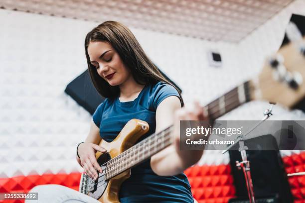 young woman playing bass in studio - woman in guitar making studio stock pictures, royalty-free photos & images