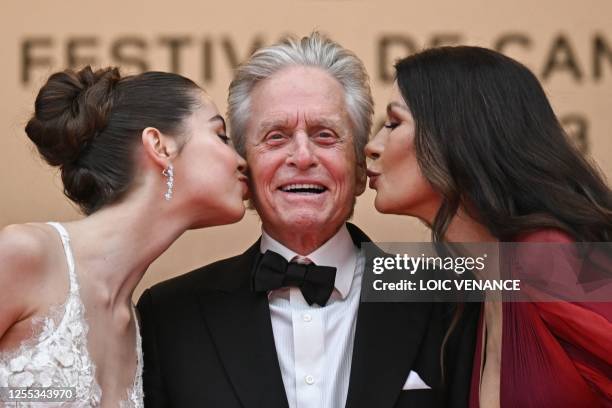 British actress Catherine Zeta-Jones and her daughter Carys kiss US actor Michael Douglas on the cheek as they arrive for the opening ceremony and...