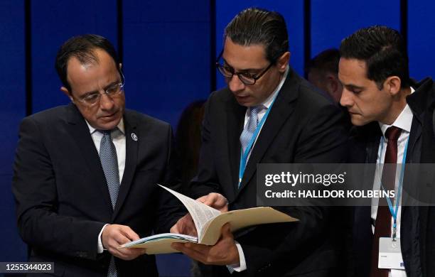 Cyprus' President of the Republic Nikos Christodoulides and Cyprus' Foreign Minister Constantinos Kombos browse a document as he prepares to attend...