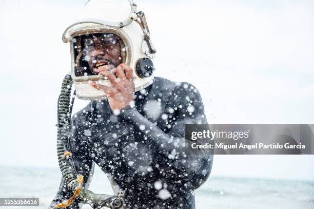 astronaut with wetsuit taking off his helmet. - earth angel stockfoto's en -beelden