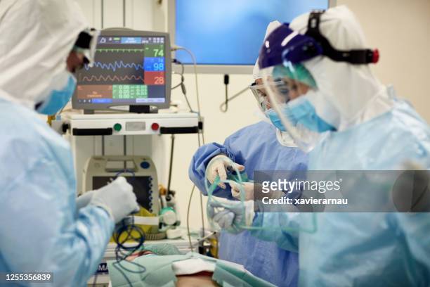 surgical team in full protective gear preparing to operate - state of emergency stock pictures, royalty-free photos & images
