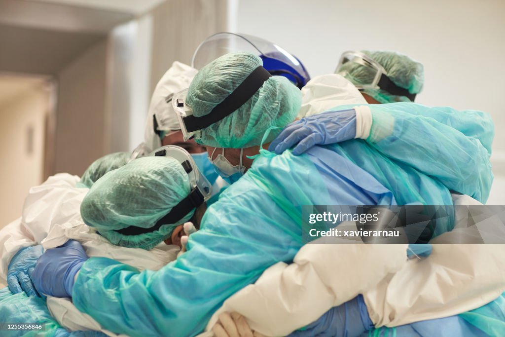 Médicos y enfermeras con brazos alrededor de los demás en apoyo