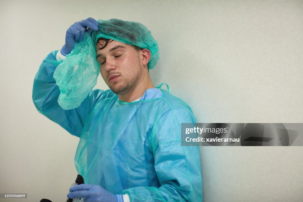 Exhausted Young Medical Worker Removing Protective Wear