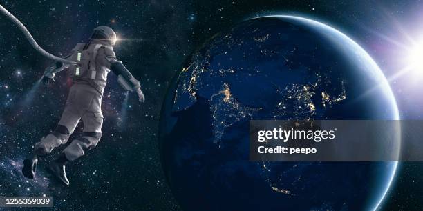 astronaut on space walk mira las luces del planeta tierra - astronauta fotografías e imágenes de stock