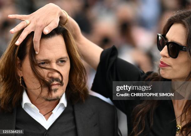 French actress and director Maiwenn adjusts the hair of US actor Johnny Depp during a photocall for the film "Jeanne Du Barry" during the 76th...