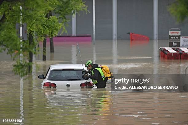 Speleological alpine rescuer looks in a car for missing persons near a supermarket in a flooded area in Cesena on May 17, 2023. Heavy rains have...