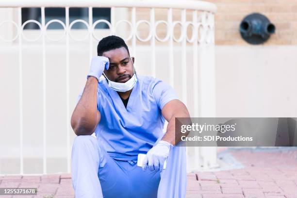 concerned nurse takes shift break outdoors - tired healthcare worker stock pictures, royalty-free photos & images