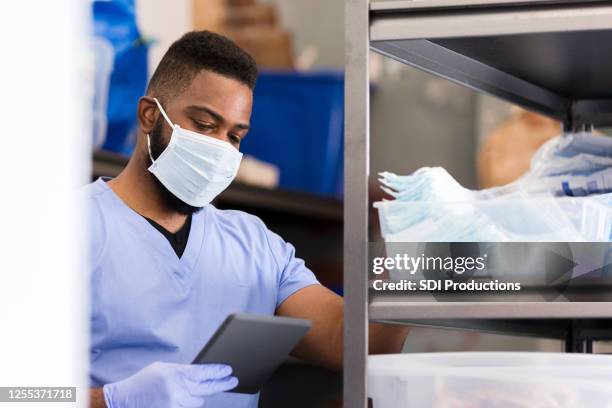 enfermera masculina revisando suministros en el almacén - material médico fotografías e imágenes de stock