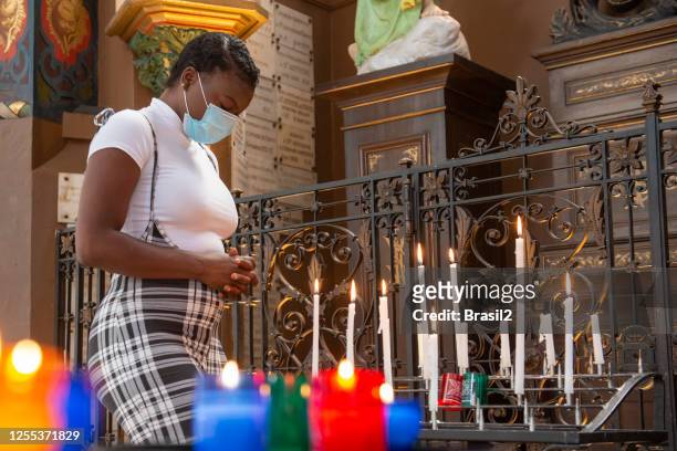 young woman lighting candles inside the church in times of coronavirus - in flames i the mask stock pictures, royalty-free photos & images