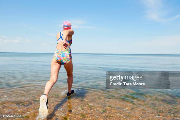 mature woman running into sea - holiday blue sky stock pictures, royalty-free photos & images