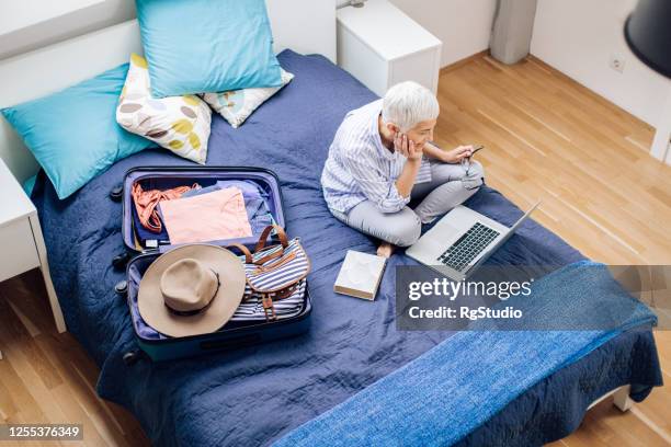 happy mature woman exploring her travel destination before going on a journey - travel insurance stock pictures, royalty-free photos & images