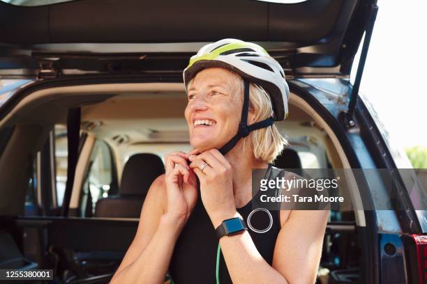 woman putting on cycling helmet - women on bike stockfoto's en -beelden