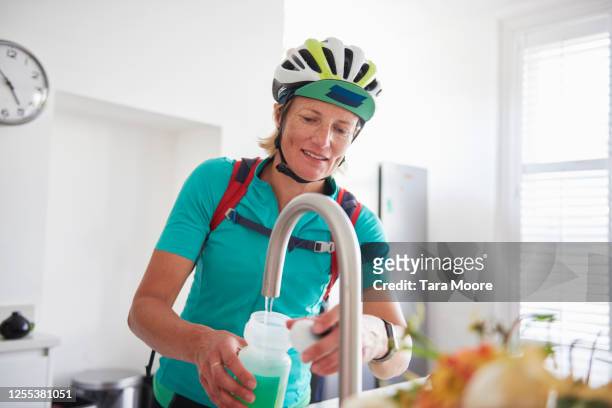 female cyclist with water bottle in house - filling stock pictures, royalty-free photos & images