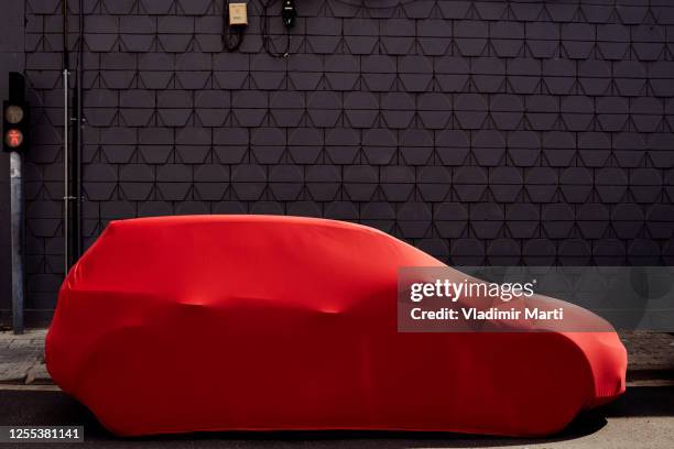 red covered car on street - covered car stock-fotos und bilder