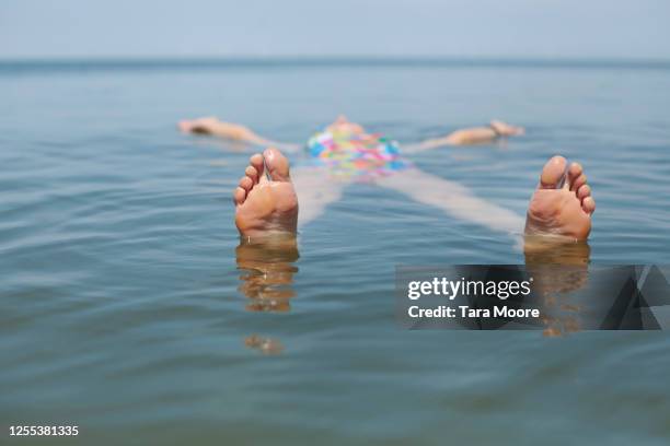 mature woman floating in sea - escape stockfoto's en -beelden