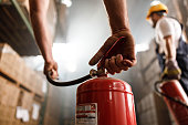 Close up of using fire extinguisher in a warehouse.
