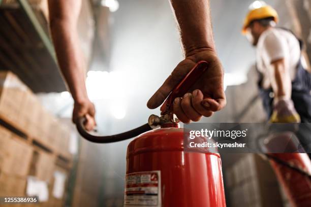 close up of using fire extinguisher in a warehouse. - fire extinguisher stock pictures, royalty-free photos & images