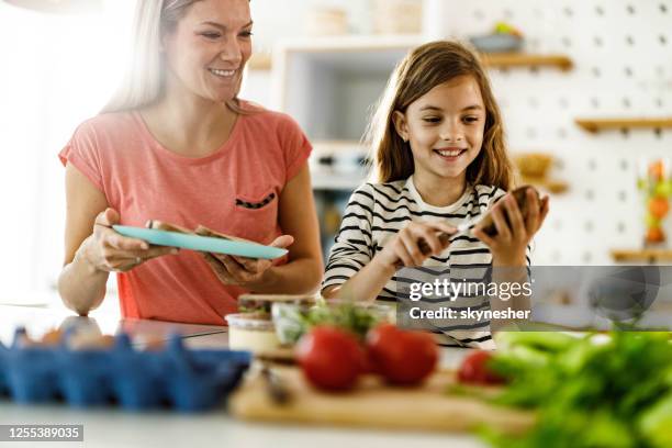 glad ensamstående mamma och dotter gör frukost i köket. - göra en macka bildbanksfoton och bilder