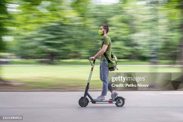 man with face mask riding his electric scooter in the city - man on scooter stock pictures, royalty-free photos & images