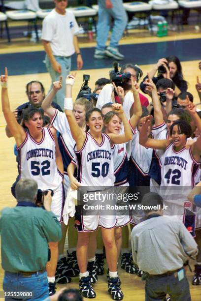 Photographers gather around Kara Wolters , Rebecca Lobo , and Nykesha Sales and other teammatees as they raise their arms in celebration after a...