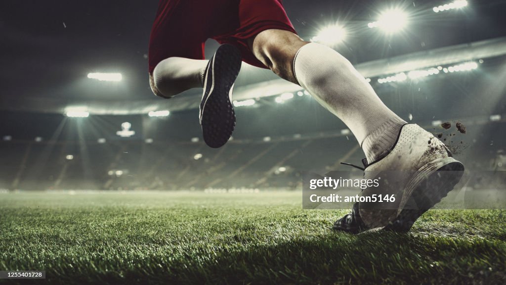 Close up football or soccer player at stadium in flashlights - motion, action, activity concept