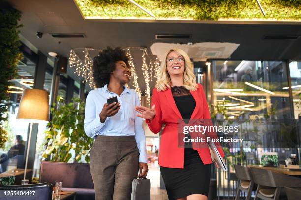 cheerful businesswoman talking while entering a hotel on a business travel - corporate storytelling stock pictures, royalty-free photos & images