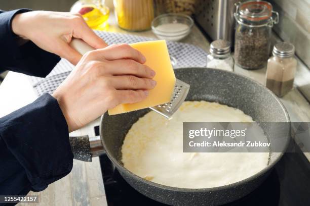 cooking italian pasta with cream sauce and basil, at home. rub the parmesan cheese and add it to the sauce with garlic. vegetarian food. step-by-step instructions, do it yourself. step 8. - grater stock pictures, royalty-free photos & images