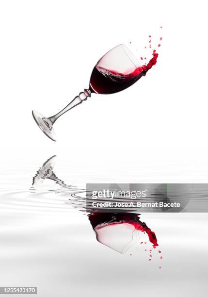 glass of wine that crashes into the ground, reflected on a surface of water. - glass half full party stock pictures, royalty-free photos & images