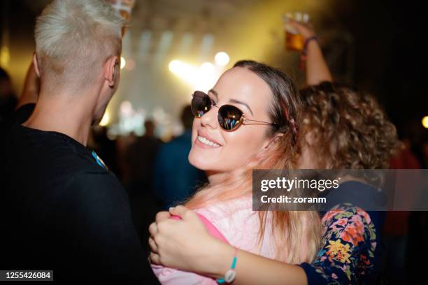 young woman with friends on live event, looking at camera over shoulder - fan concert stock pictures, royalty-free photos & images