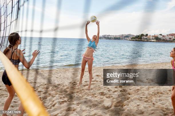 young woman in bikini setting the volleyball to her team mate - setter stock pictures, royalty-free photos & images