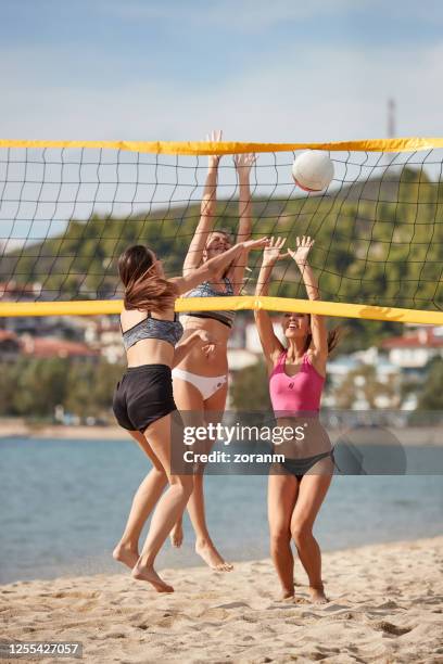 young woman spiking in the net, opponents jumping in block - beach volleyball spike stock pictures, royalty-free photos & images