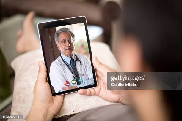 uomo in videoconferenza con medico - india doctor foto e immagini stock