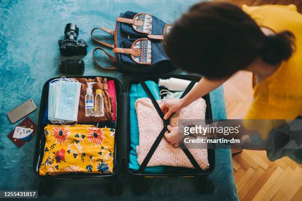 vrouw die koffer voor reis inpakt - reisbestemmingen stockfoto's en -beelden