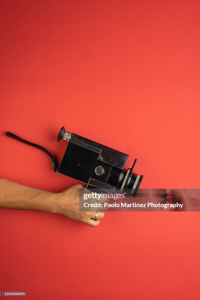 Woman Holding Retro 8mm Camera On Red Background