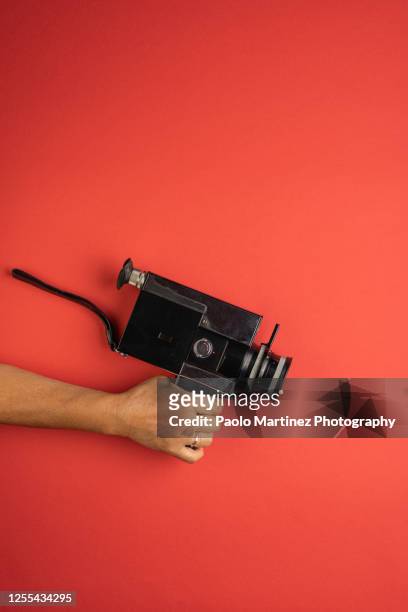woman holding retro 8mm camera on red background - film director stock-fotos und bilder