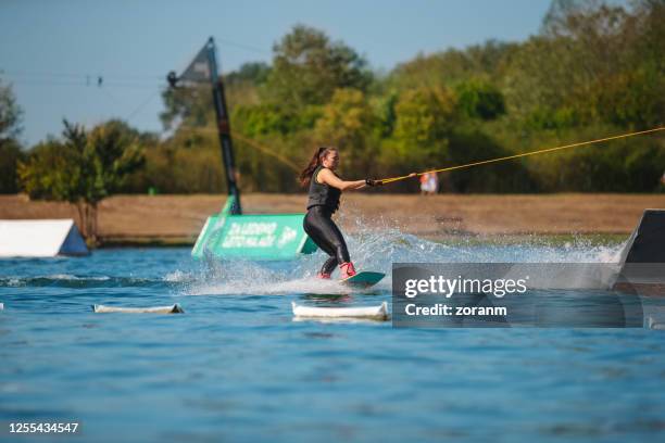 young woman wakeboarding between the sports ramps - waterskiing stock pictures, royalty-free photos & images