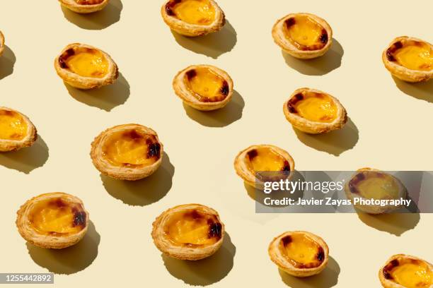 many egg tarts on yellow colored background - pastel de nata stock pictures, royalty-free photos & images