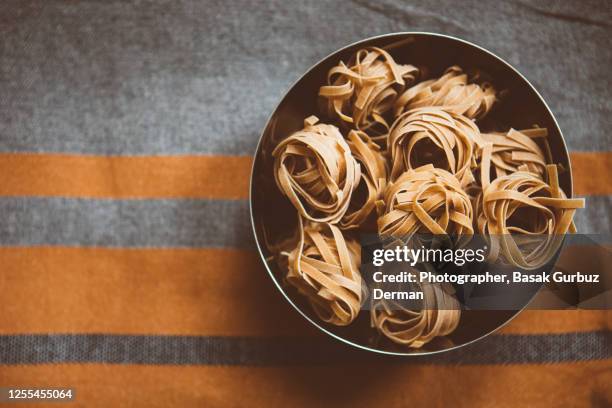 wholemeal tagliatelle in a bowl on a kitchen linnen tablecloth - wholegrain pasta stock pictures, royalty-free photos & images