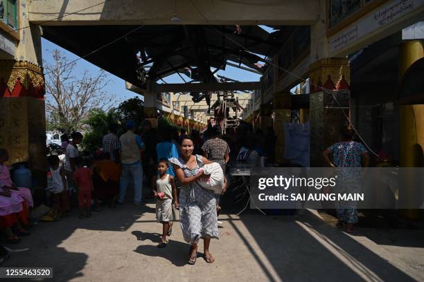 Woman carry a bag of rice bag handed out by the UN World Food Programme at a monastery in Sittwe on May 17 in the aftermath of Cyclone Mocha's...