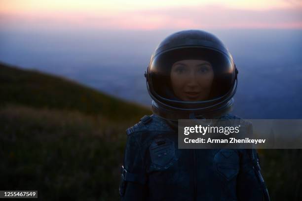 astronaut woman in space costume and helmet during sunset - astronaut portrait stock-fotos und bilder