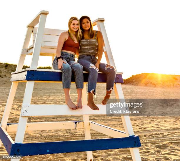 le soleil se couche derrière des amis assis sur la chaise de sauveteur - bigger photos et images de collection