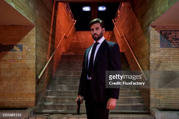 secret service special agent standing in a subway carrying a gun - secret service stock pictures, royalty-free photos & images