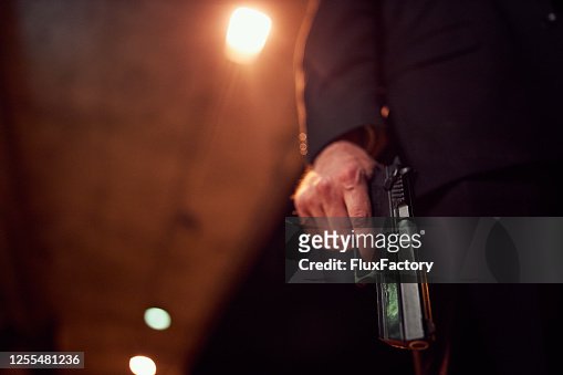 Unrecognizable person holding a handgun at night