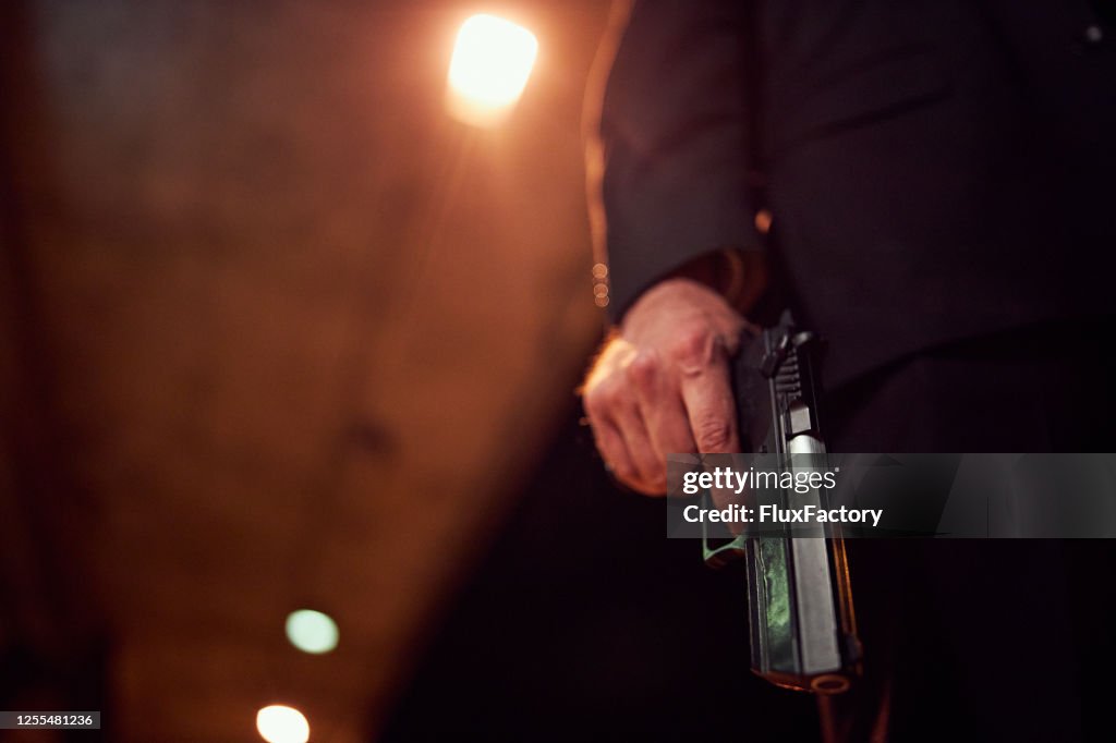 Unrecognizable person holding a handgun at night