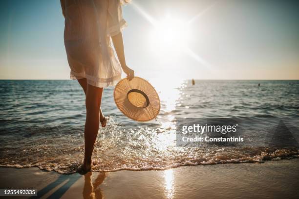 las piernas de la mujer salpicando agua en la playa - luz del sol fotografías e imágenes de stock